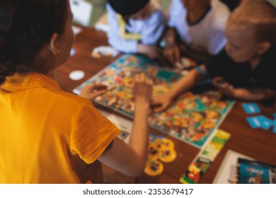 Process of playing board game and having fun with friends and family in room indoors, board game concept, group of kids children play board games at the table, roll the dice 
