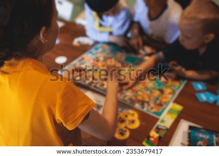 Process of playing board game and having fun with friends and family in room indoors, board game concept, group of kids children play board games at the table, roll the dice 