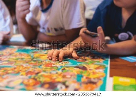 Process of playing board game and having fun with friends and family in room indoors, board game concept, group of kids children play board games at the table, roll the dice 