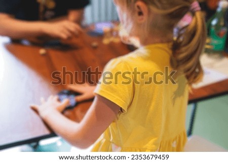Process of playing board game and having fun with friends and family in room indoors, board game concept, group of kids children play board games at the table, roll the dice 