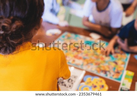 Process of playing board game and having fun with friends and family in room indoors, board game concept, group of kids children play board games at the table, roll the dice 