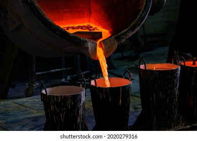 The Process Of Pouring Hot Metal Into Special Molds From A Large Container Into A Small One, The Red Molten Metal Pours Down