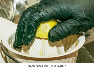 The Process Of Preparing An Alcoholic Drink Limoncello At Home. Male Hands In Black Gloves Make Lemon Juice On A Juicer.