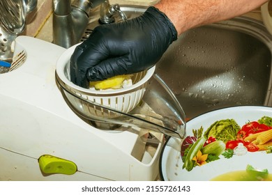 The Process Of Preparing An Alcoholic Drink Limoncello At Home. Male Hands In Black Gloves Make Lemon Juice On A Juicer.