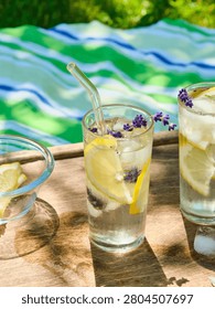 The process of preparing cold water with lemon and ice cubes in tall glasses outdoors in summer. Refreshing drinks.