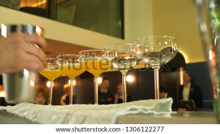 the process of preparing five cocktails from the juice of citrus and mango pulp, the barman takes a shaker and pours out the cocktail in the last two glasses, filtering the whipped liquid in the