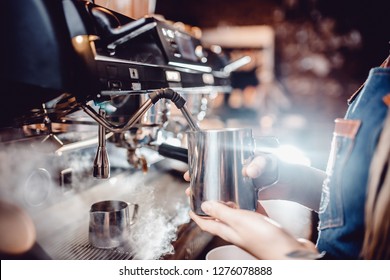 Verfahren zur Herstellung von Milchschaum für Cappuccino, Heizung und Peitschen. Barista kontrolliert die Temperatur, indem er den Krug in den Händen hält.