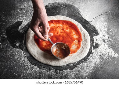 The process of preparing pizza. The chef pours tomato sauce over the rolled dough. Horizontally close up. - Powered by Shutterstock