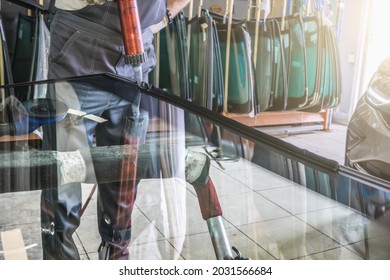 Process Of Preparing Windshield For Replacement In Car Service. Worker Applies Special Adhesive Sealant To Windscreen Before Installation On Auto