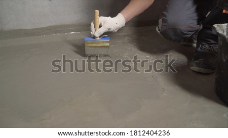 The process of priming the floor with a solution. Waterproofing a concrete floor. repair cracked floor in front of a waterproof cement treatment system