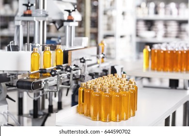 Process of producing cosmetics. Many glass bottles with yellow liquid standing near conveyor on factory. Row line of glass bottles on factory. Innovation and creation concept. Producing new products