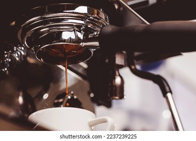 Process professional espresso pouring from coffee machine in cafe, warm toning.