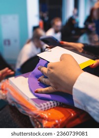 Process of receiving gift bag package for conference participants before start, with a leaflet handout, notebook notepad, t-shirt, mug, pen, pencil, corporate gifts and souvenirs for employees 
