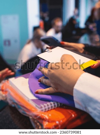 Process of receiving gift bag package for conference participants before start, with a leaflet handout, notebook notepad, t-shirt, mug, pen, pencil, corporate gifts and souvenirs for employees 