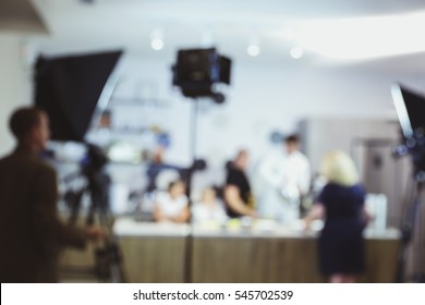 The Process Of Recording A TV Program In The Culinary Studio, Blurred Background. Video Light Stands With Equipment And Crew.