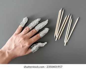 The process of removing gel polish from nails. Nails wrapped in foil on a gray background. - Shutterstock ID 2350401957