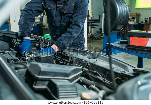 the process of replacing the car battery in the\
garage, a worker removes the old battery, replaces and tests a new\
battery.