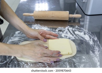 The Process Of Rolling Out Puff Pastry With Butter Layers On A Table With Flour And Rolling Pin. Workpiece For Pastry And Croissants