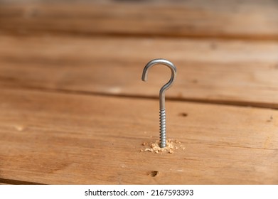 The process of screwing a half ring screw into a drilled hole. The C-hook anchor screw is installed in a wooden surface. Close-up. Selective focus.