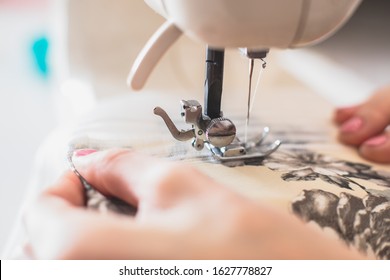 Process Of Sewing The Curtains At Home, Close Up Of Curtain Tape On The Sewing Machine, Hemming, Tailoring, Repairing And Stitching Cloth And Dress, With The Hand Of Female Dressmaker In Background
