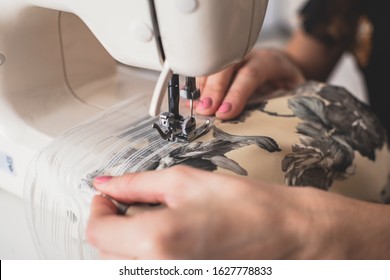 Process Of Sewing The Curtains At Home, Close Up Of Curtain Tape On The Sewing Machine, Hemming, Tailoring, Repairing And Stitching Cloth And Dress, With The Hand Of Female Dressmaker In Background
