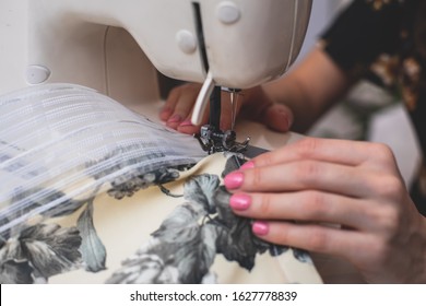 Process Of Sewing The Curtains At Home, Close Up Of Curtain Tape On The Sewing Machine, Hemming, Tailoring, Repairing And Stitching Cloth And Dress, With The Hand Of Female Dressmaker In Background
