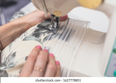 Process Of Sewing The Curtains At Home, Close Up Of Curtain Tape On The Sewing Machine, Hemming, Tailoring, Repairing And Stitching Cloth And Dress, With The Hand Of Female Dressmaker In Background
