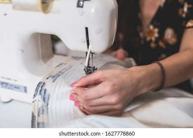 Process Of Sewing The Curtains At Home, Close Up Of Curtain Tape On The Sewing Machine, Hemming, Tailoring, Repairing And Stitching Cloth And Dress, With The Hand Of Female Dressmaker In Background
