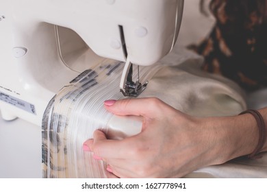 Process Of Sewing The Curtains At Home, Close Up Of Curtain Tape On The Sewing Machine, Hemming, Tailoring, Repairing And Stitching Cloth And Dress, With The Hand Of Female Dressmaker In Background
