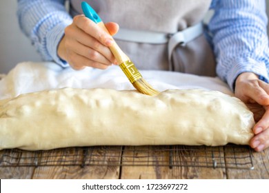 The process of smearing the cake with a brush. The girl greases the cake with a brush. Cooking apple strudel at home in the kitchen. Mom in an apron lubricates the cake. The pie is sent to the oven.
