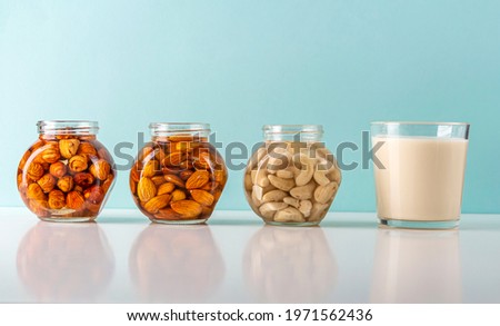 Process of soaking various nuts: almonds, hazelnuts, cashew in water to activate and glass of vegetable milk. Home Cooking: making plant based organic veggie Milk, lactose free