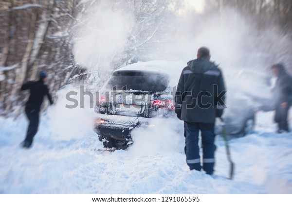 Process of taking out suv car stuck in snow, men\
digging and pushing the car out of snow, concept of winter problems\
with car