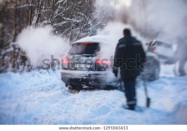 Process of taking out suv car stuck in snow, men\
digging and pushing the car out of snow, concept of winter problems\
with car