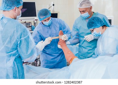 Process Of Trauma Surgery Operation. Group Of Surgeons In Operating Room With Surgery Equipment. Medical Background