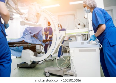 Process Of Trauma Surgery Operation. Group Of Surgeons In Operating Room With Surgery X-ray Equipment. Medical Background