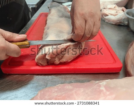 process of trimming excess fat from a large piece of raw meat using a boning or trimming knife. 