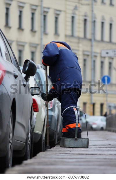 Process of urban street cleaning sweeping. Worker\
with broom and dust\
pan.