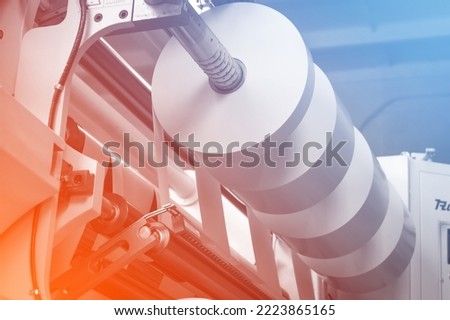 The process of winding paper self-adhesive tape into rollers of printing offer paper for printing houses. Close-up of the paper cutting and rewinding machine. Selective focus