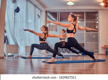 Process of yoga exercises with three beautiful young girls at gymnastic studio.