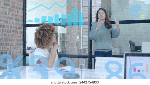 Processing data over diverse casual businesswomen discussing at office presentation. Casual business, data, digital interface, connection, office and communication digitally generated image.