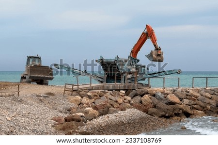 Processing stones for beach reconstruction. Jaw crusher on stone crushing at beach. Concrete recycling shredding machine. Shore protection and Beach regeneration. Replenishment of sand on beach. 