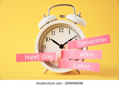 Procrastination, delay and postpone concept. Alarm clock with sticky notes   later, tomorrow, next day and after on the yellow background
