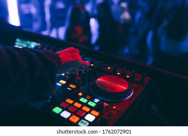 producer  DJ mixer in a nightclub with glowing plays musical rave Dubstep Electronic Trance composition with modern midi controller device in nightclub Live.Musical production process for artists.