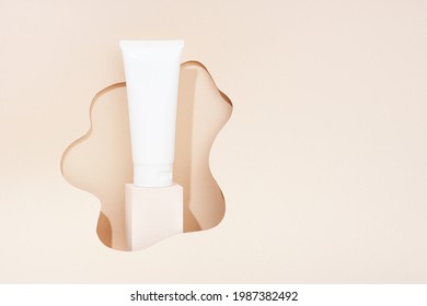 Product photography with props. White cosmetic tube on light color background. Minimal concept.