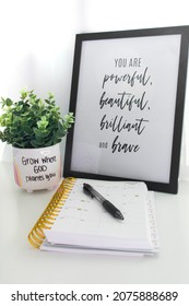 A Product Photography Set Up Of A Plant, Notebook, And Motivational Sign.