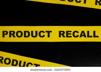 Product recall alert, caution and warning concept. Yellow barricade tape with word in dark black background.