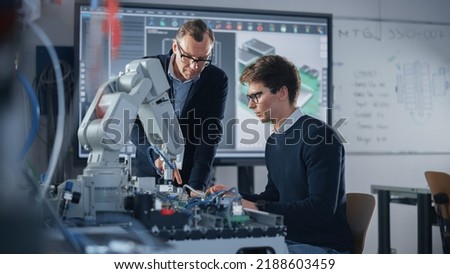 Product Supervisor Consults Young Engineer Working with Optimization of Robot Arm. People Doing Robotic Hand Maintenance Ideas. High-Tech Science and Engineering Concept. Medium Shot