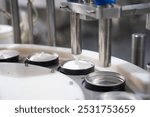 Production line of beauty and healthcare products at plant or factory. Process of manufacturing and packaging cosmetics goods, hand cream in metal container. Close up.