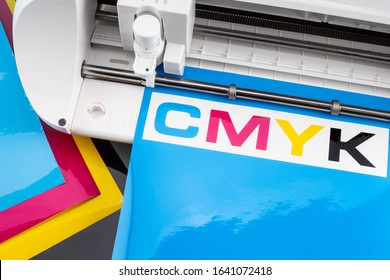 Production Making CMYK Sticker With Plotter Cutting Machine On Cyan Blue Colored Vinyl Film Advertising Industry Diy Design On Concept Background.