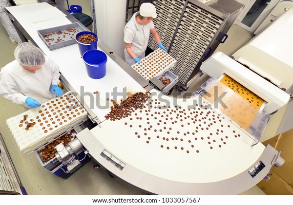 Production of pralines in a\
factory for the food industry - conveyor belt worker with chocolate\
